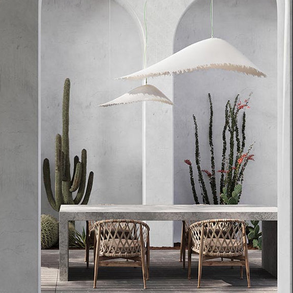 Modern outdoor dining area with a concrete table and chairs on a wooden deck, featuring cacti and a white pendant light.