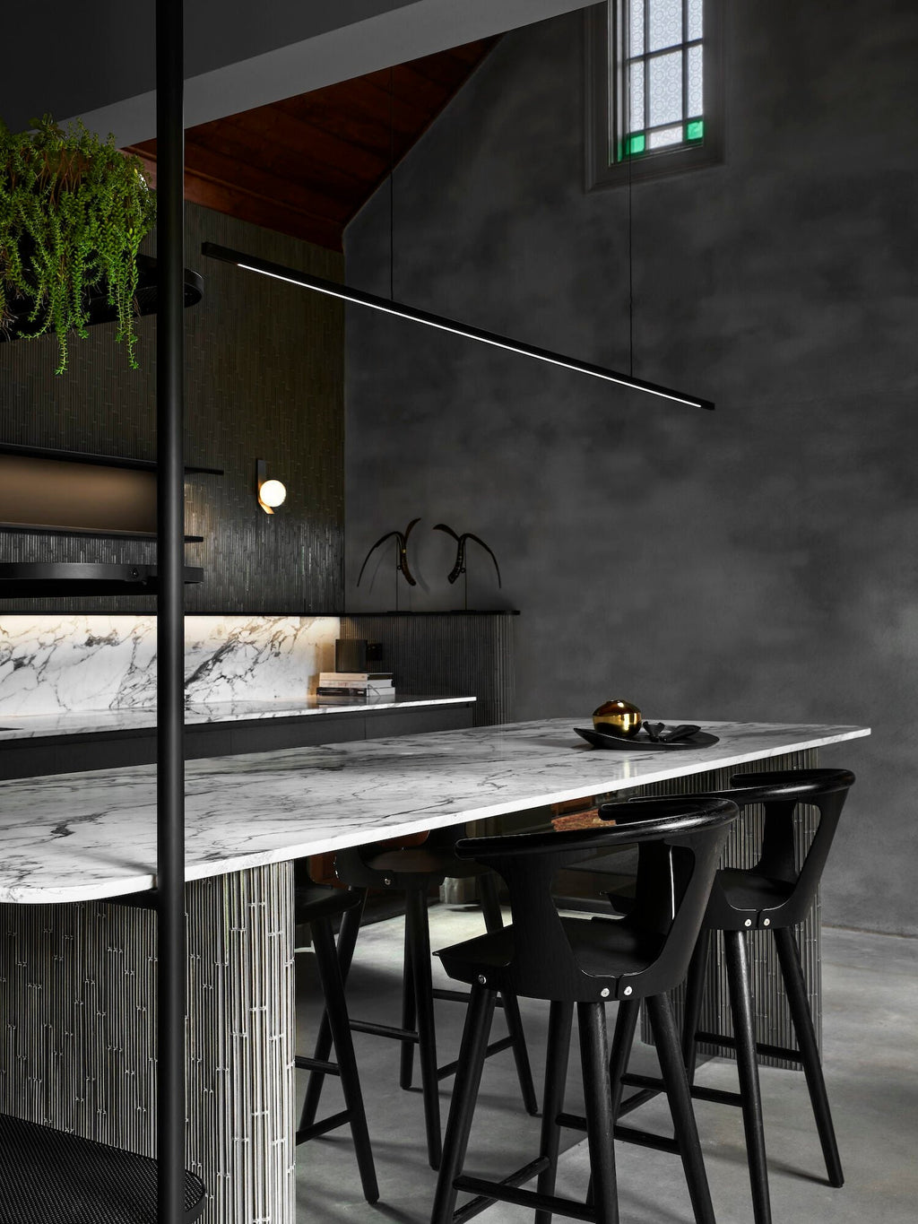 Highline Linear Pendant in Black over Marble Kitchen Island with Dark Grey Woodwork and Wall Light