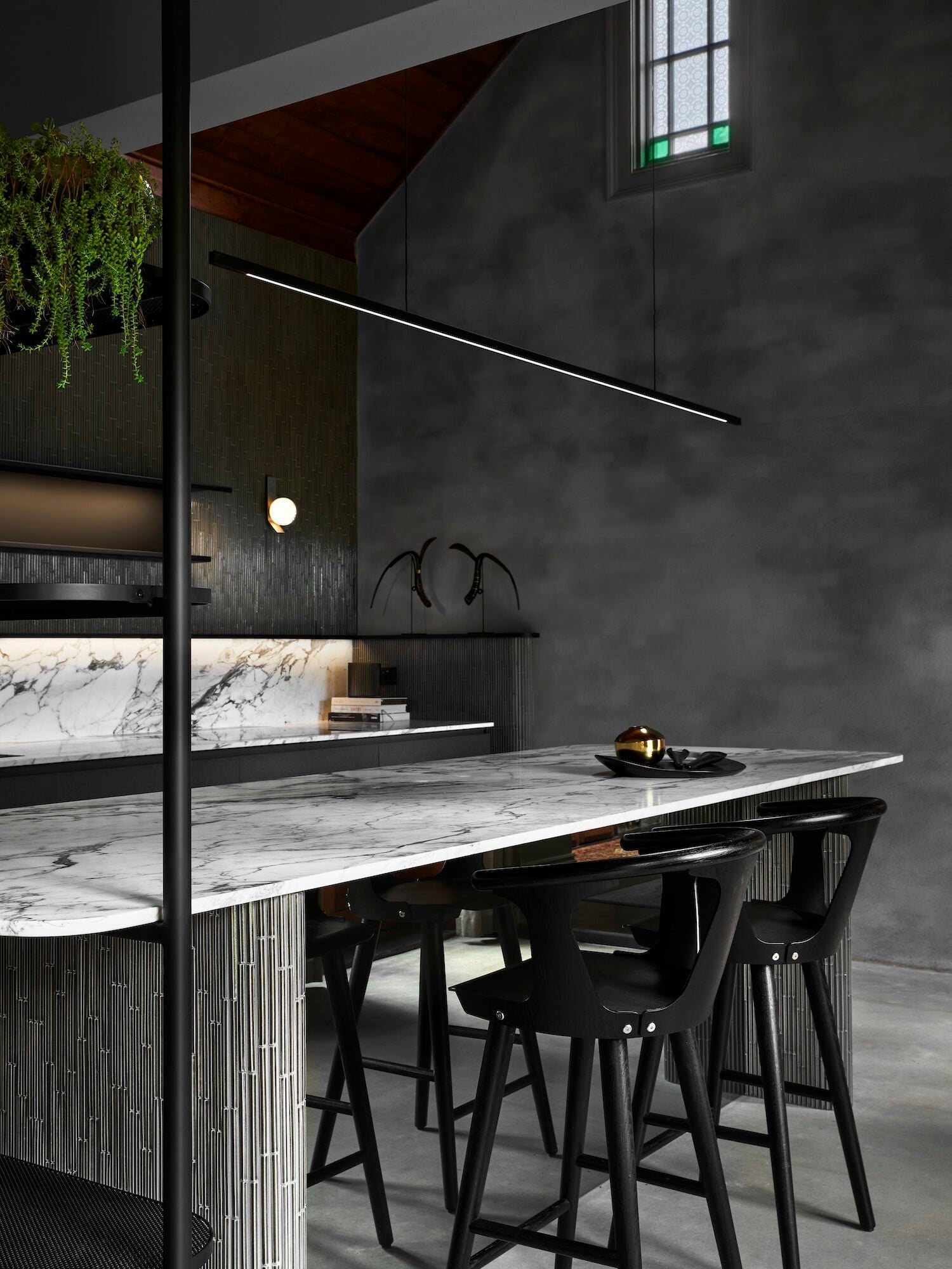 Highline Linear Pendant in Black over Marble Kitchen Island with Dark Grey Woodwork and Wall Light