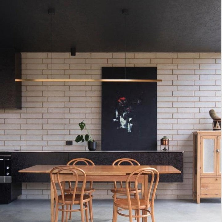 Highline Linear Pendant in Brass over Small Wooden Dining Table