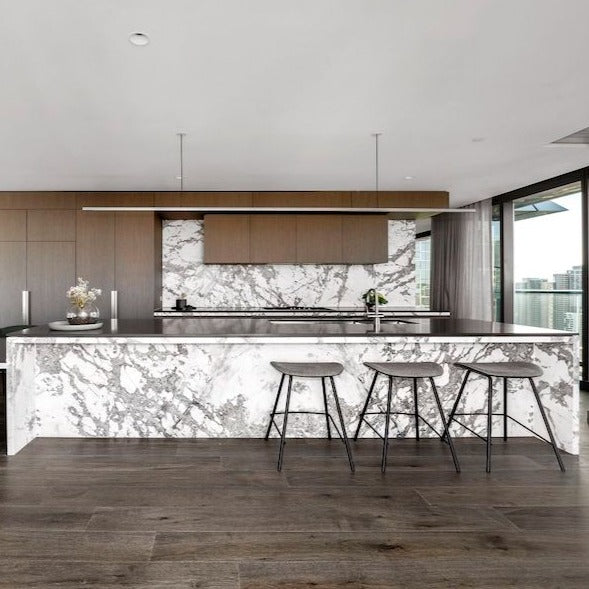Highline Linear Pendant in White over Carrara Marble Kitchen Island with Dark Wood Floors